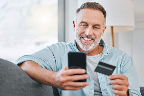 © K Davis/peopleimages.com - stock.adobe.com Foto: Mann mit Smartphone und Kredikarte