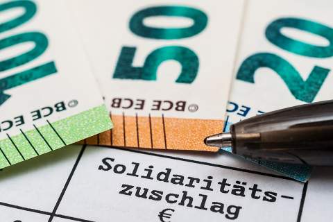 © Stockfotos-MG - stock.adobe.com Foto: Schriftzug Solidaritätszuschlag und Geldscheine
